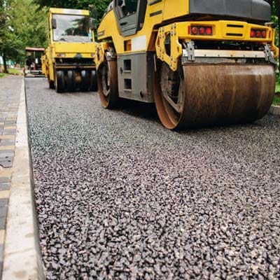 Commercial asphalt surfacing with heavy-duty rollers compacting freshly laid tar on a roadway