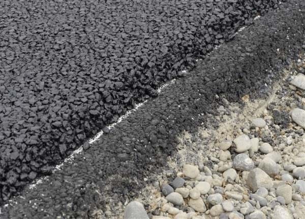 Cross-section of a newly paved asphalt road, showing smooth tar surface over underlying materials.