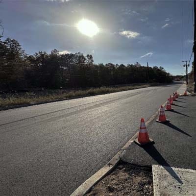 Freshly repaired asphalt road with traffic cones, showing minimal traffic disruption during cold mix asphalt application