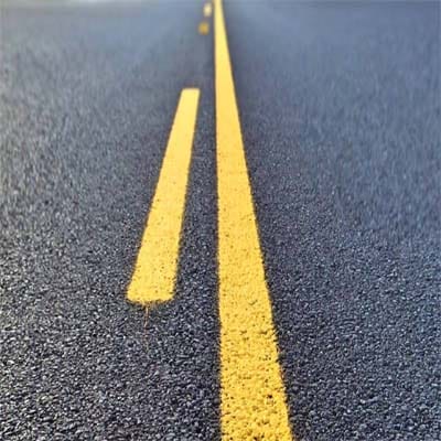 Freshly paved asphalt road using penetration grade bitumen with clear yellow line marking