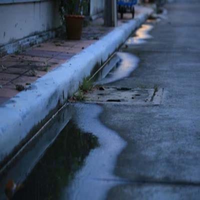 Standing water on pavement caused by poor drainage system near curb