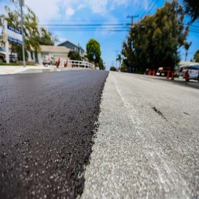 Fresh slurry seal application on urban road showing contrast between treated and untreated surface