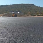 Smooth finished tar surface of a large paved area in front of a hillside property, ready for line marking