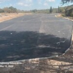 Wide tarred area with newly finished asphalt paving at a large construction site on May 15, 2024